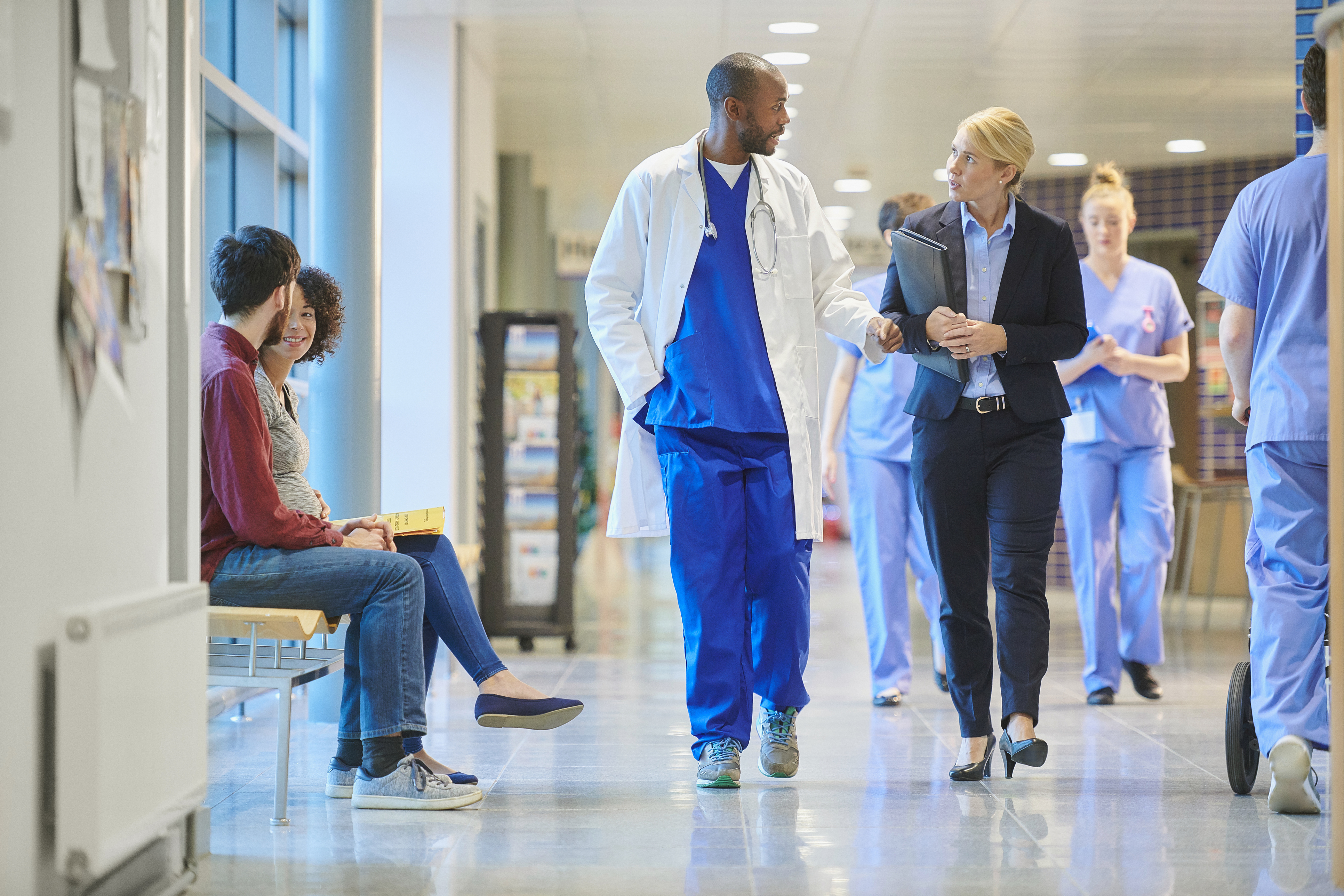 Physician and business woman walking in the hall of a hospital.